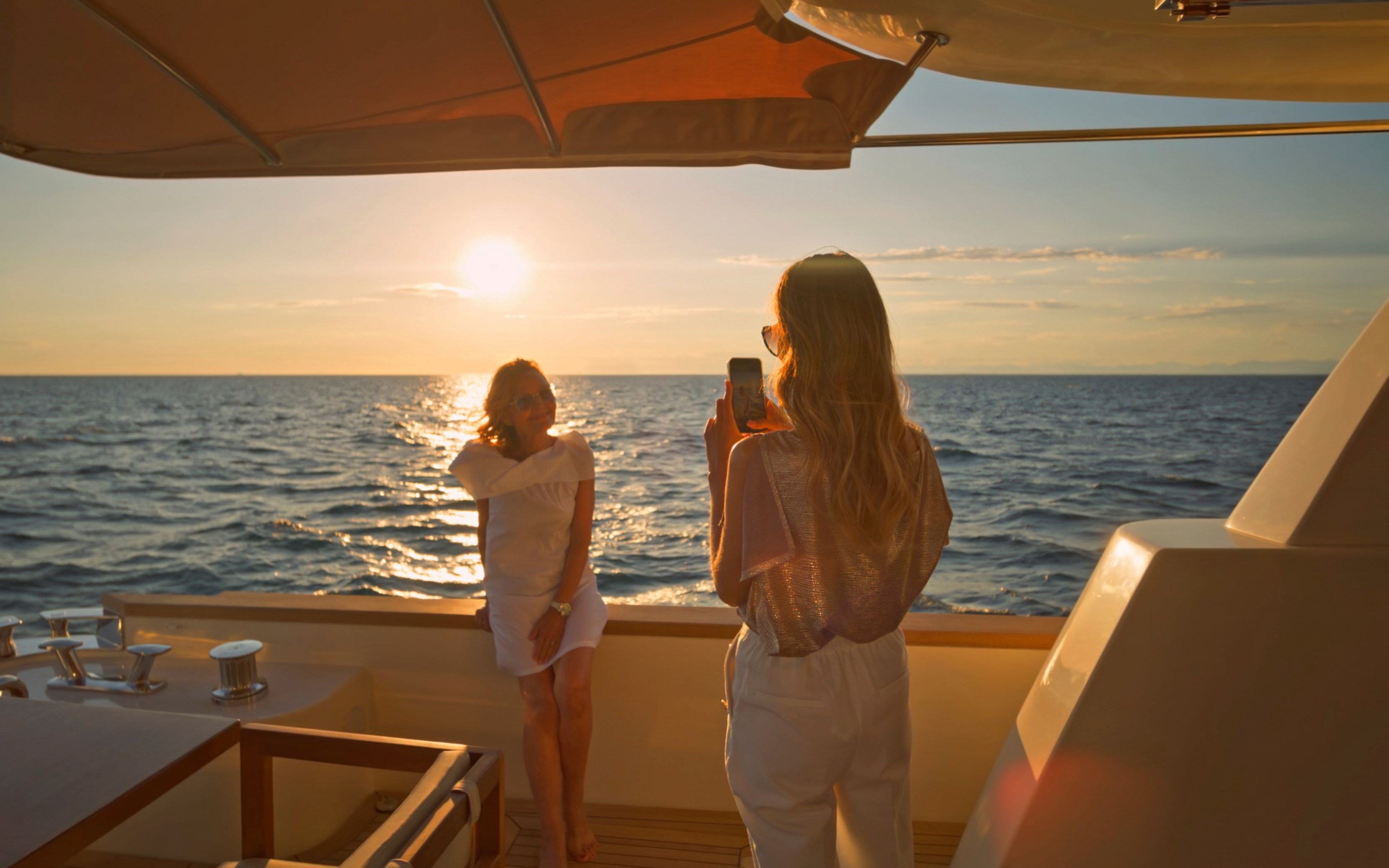 Two women enjoying Bosphorus sunset cruise, one taking a photo of the other.