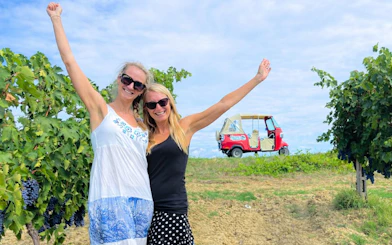 Tourists enjoying a vineyard with a vintage Tuk Tuk in San Gimignano, Chianti Hills in the background.