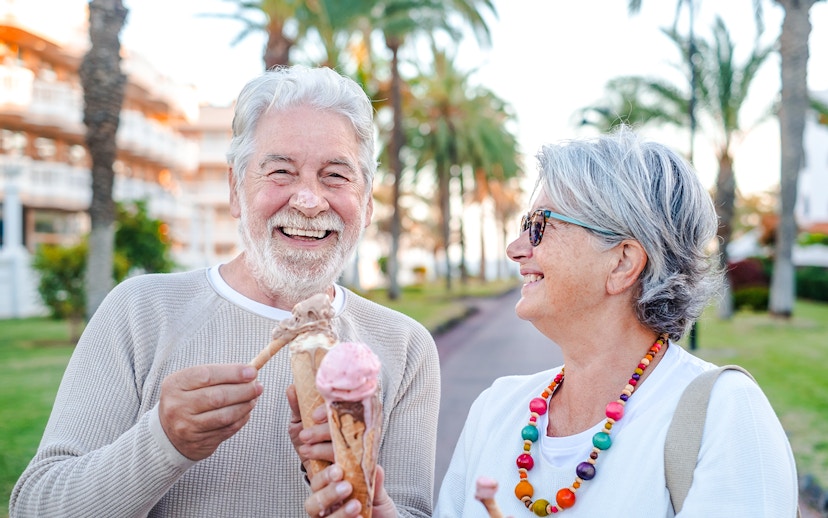 Couple enjoying ice cream on a palm-lined street.
