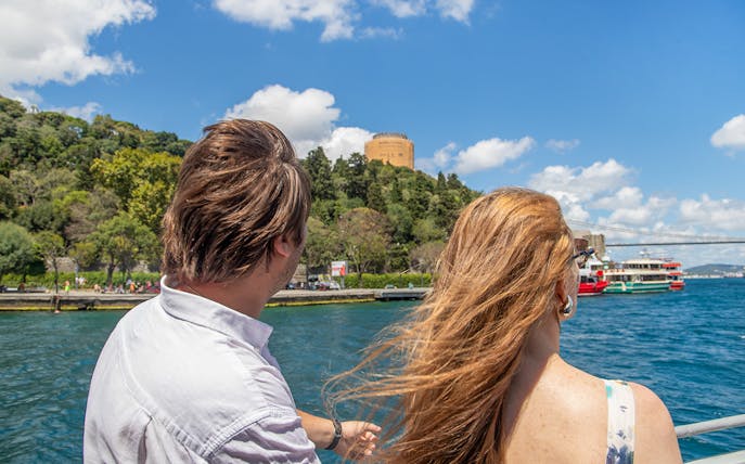 Couple enjoying a Bosphorus cruise with Rumeli Fortress in view, Istanbul.