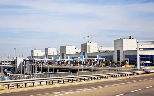 Athens airport terminal exterior with road access for minivan transfers.