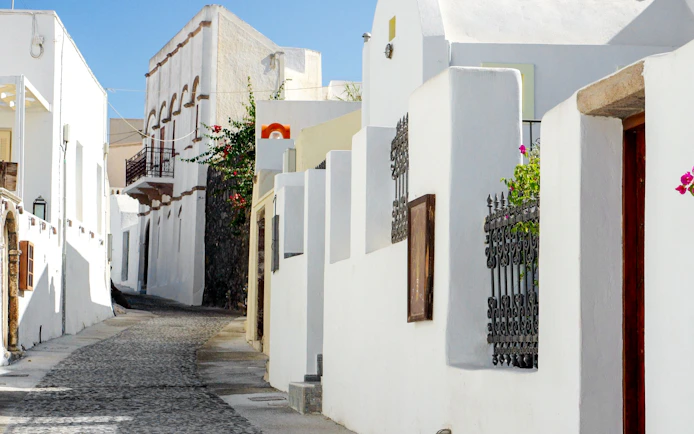 Narrow cobblestone street with whitewashed buildings in Santorini, Greece.