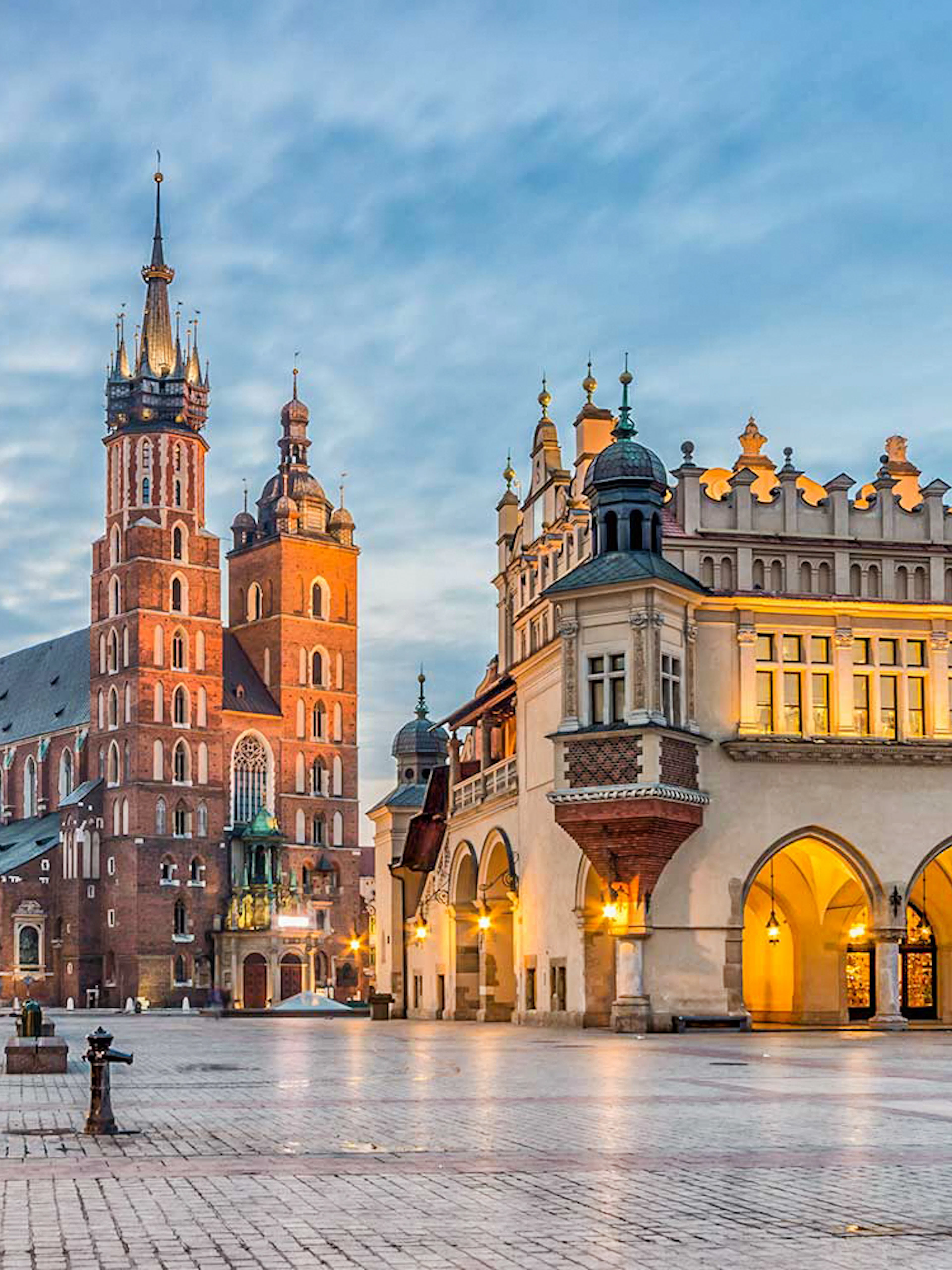 St. Mary's Church and Cloth Hall in Krakow's Main Square at dusk.