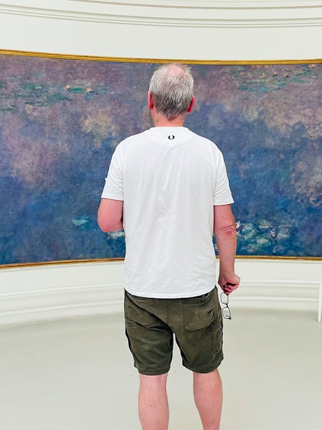 Man viewing Monet's Water Lilies at Orangerie Museum, Paris.