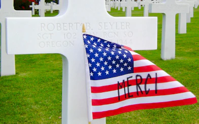 Gravestone with American flag at Normandy American Cemetery, Normandy.