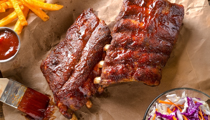 Grilled baby back pork ribs with barbecue sauce, fries, and coleslaw.