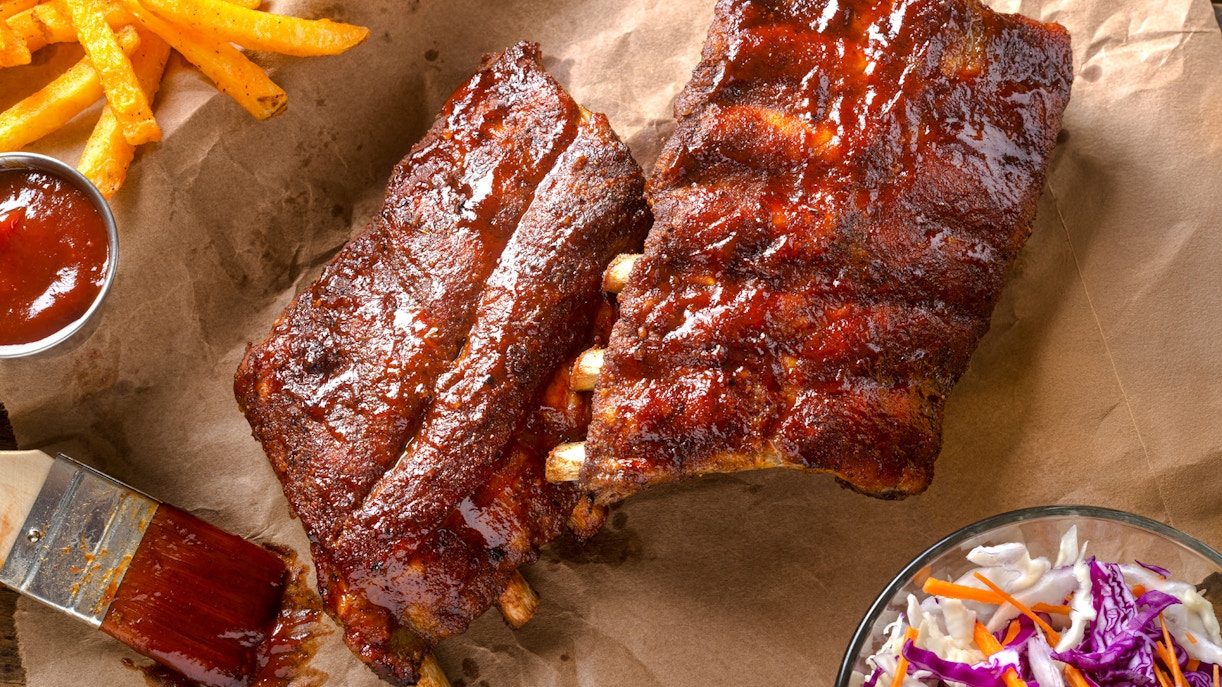 Grilled baby back pork ribs with barbecue sauce, fries, and coleslaw.