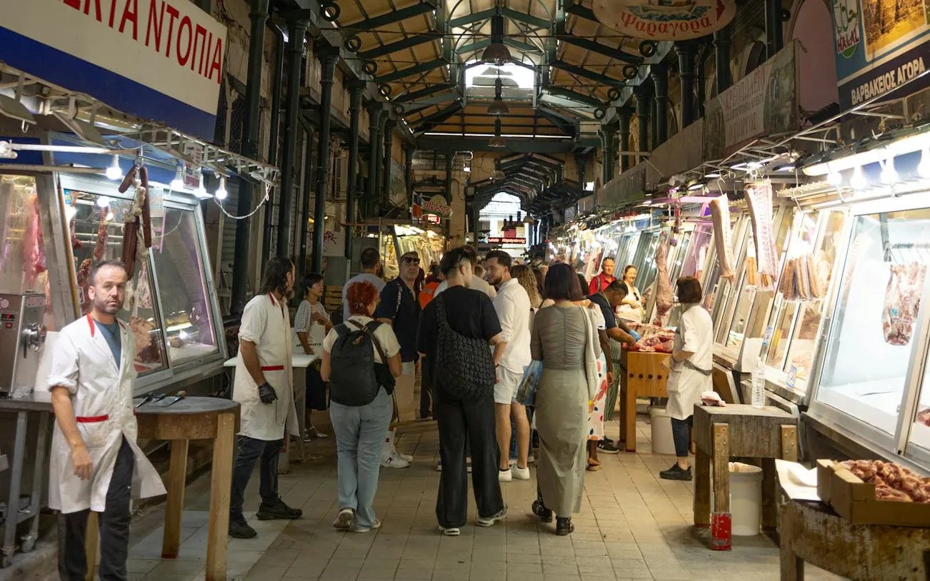 Athens market with people exploring meat stalls during food tour.