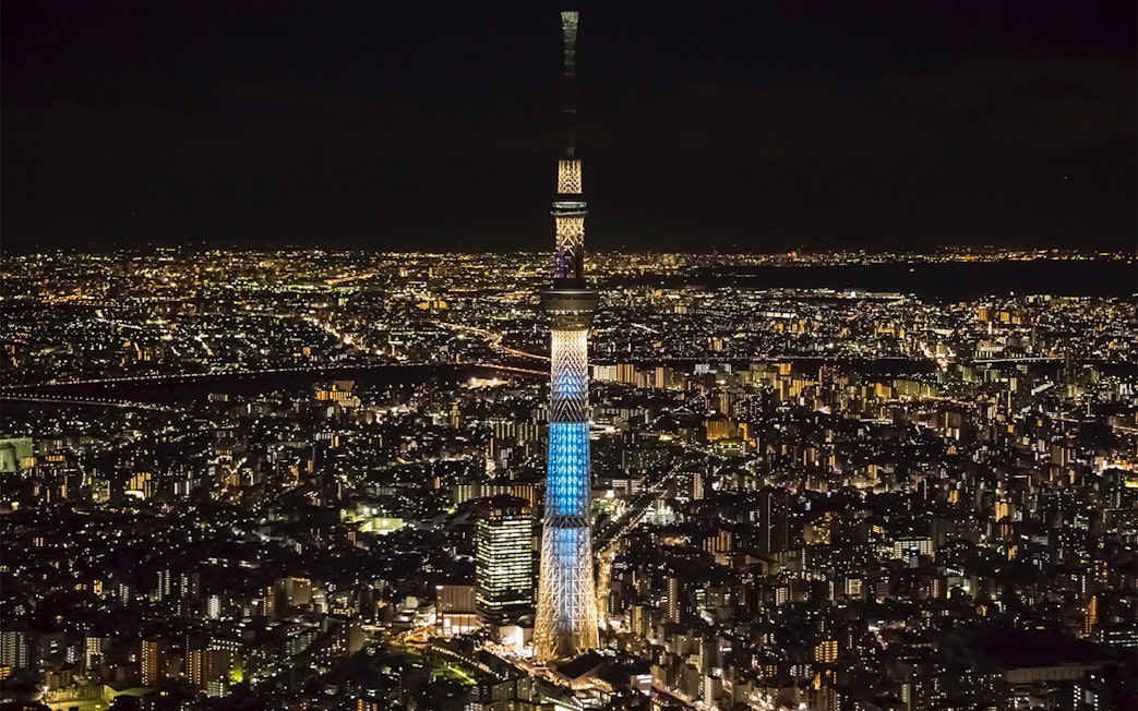 Tokyo Skytree illuminated at night, surrounded by city lights.