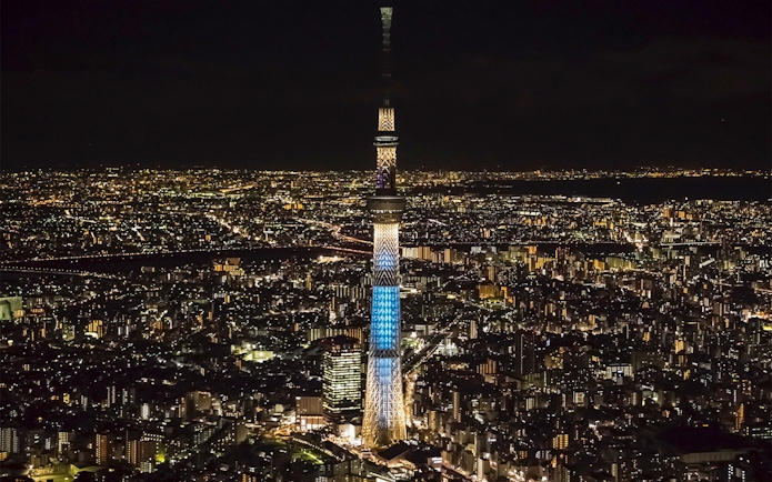 Tokyo Skytree illuminated at night, surrounded by city lights.