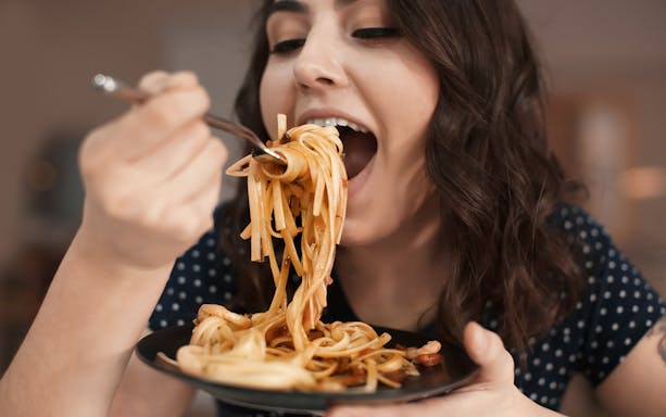 Person enjoying pasta during a food tour in Rome.