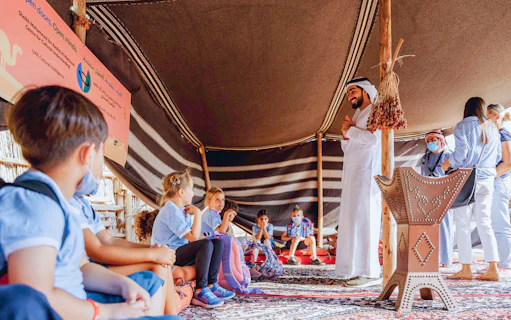 Children learning in a traditional tent during a cultural tour in Dubai.