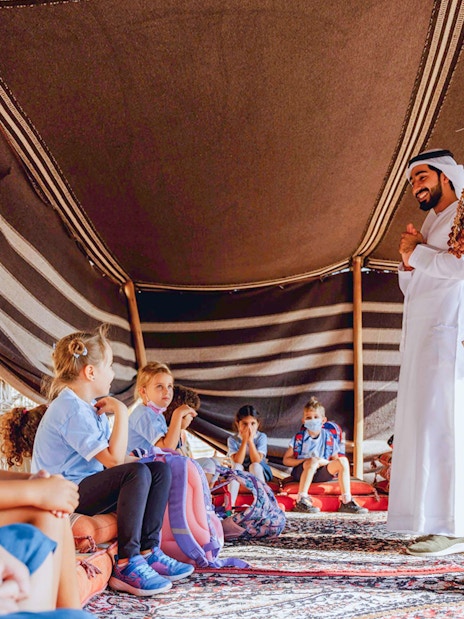 Children learning in a traditional tent during a cultural tour in Dubai.