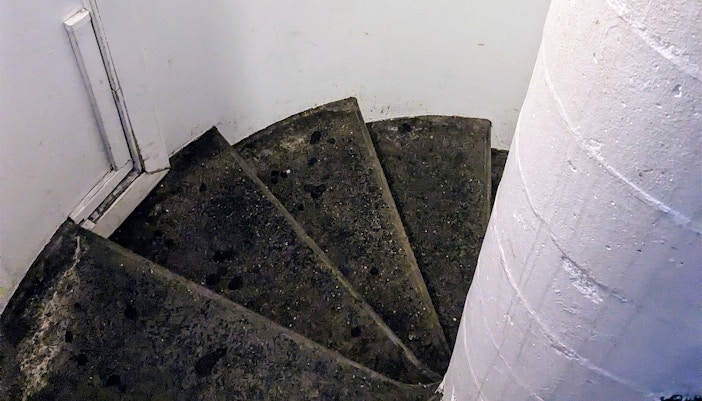 Spiral staircase in a historic building, showcasing worn stone steps.