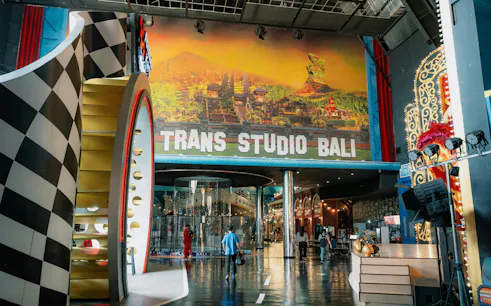 Trans Studio Bali entrance with colorful decor and visitors exploring the indoor theme park.