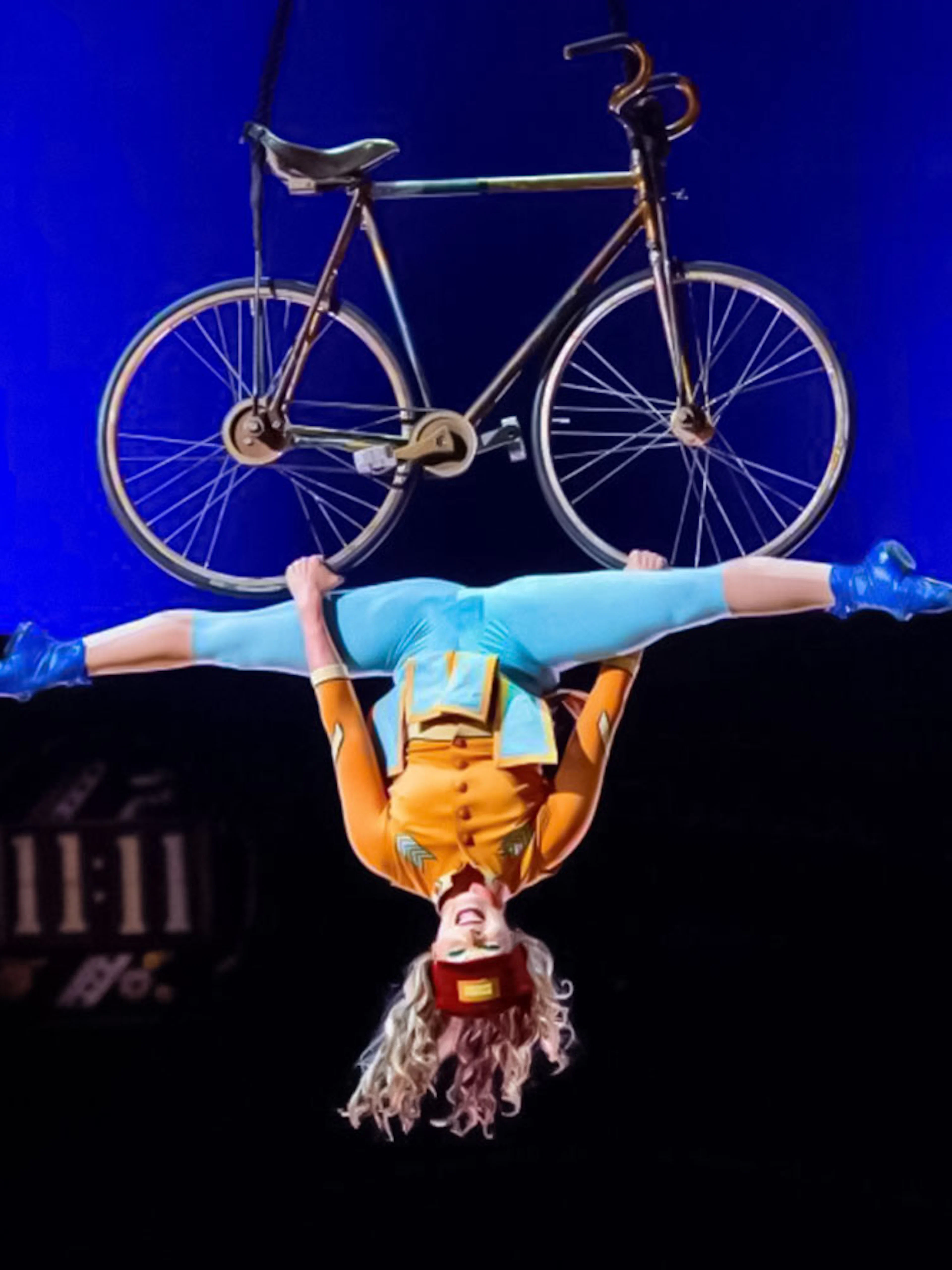 Performer hanging upside down with a bicycle at Cirque du Soleil: Kurios in Vienna.