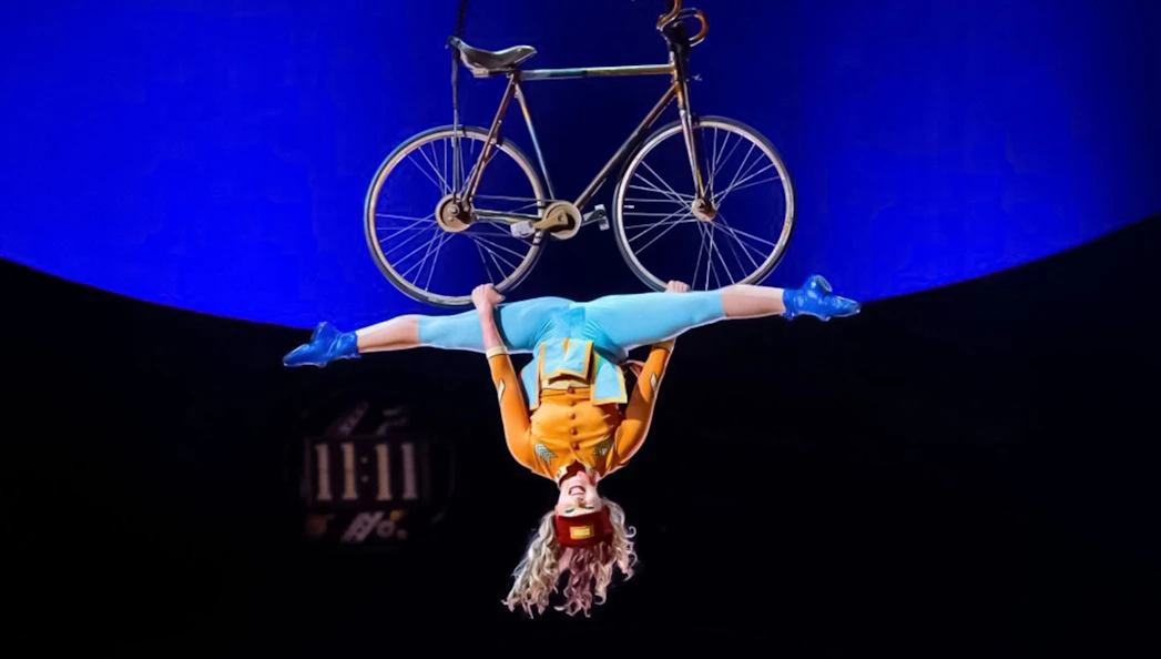 Performer hanging upside down with a bicycle at Cirque du Soleil: Kurios in Vienna.