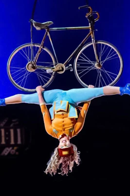 Performer hanging upside down with a bicycle at Cirque du Soleil: Kurios in Vienna.