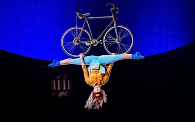 Performer hanging upside down with a bicycle at Cirque du Soleil: Kurios in Vienna.