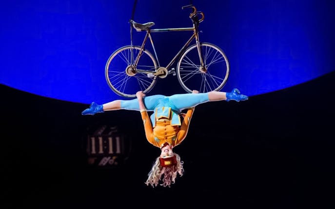 Performer hanging upside down with a bicycle at Cirque du Soleil: Kurios in Vienna.