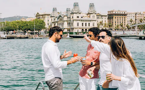 Group enjoying a catamaran cruise with Barcelona's historic buildings in the background.