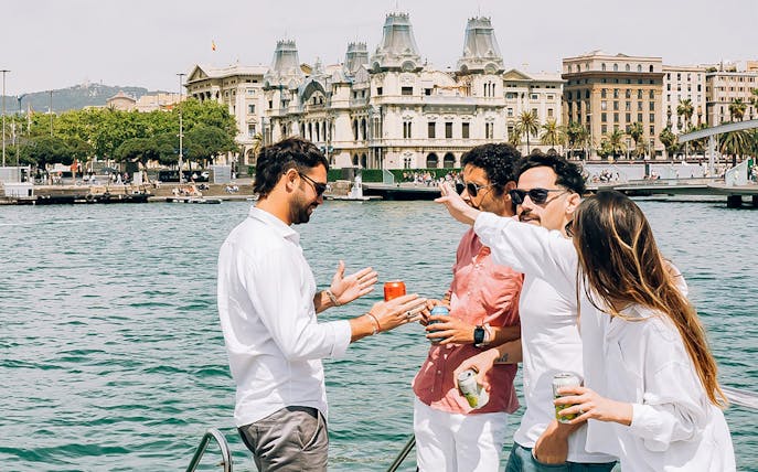 Group enjoying a catamaran cruise with Barcelona's historic buildings in the background.