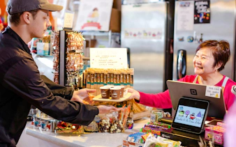 Vendor serving coffee samples at Pike Place Market during chef-guided food tour.