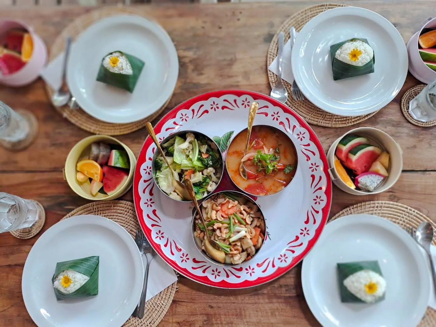 Traditional Thai meal with curry, vegetables, and fruit served on a wooden table in Krabi.