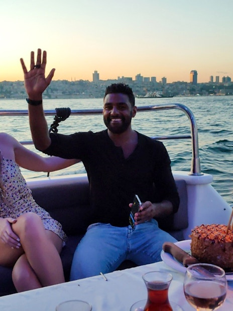 Couple enjoying sunset on Istanbul Bosphorus boat cruise with cake and sparklers.