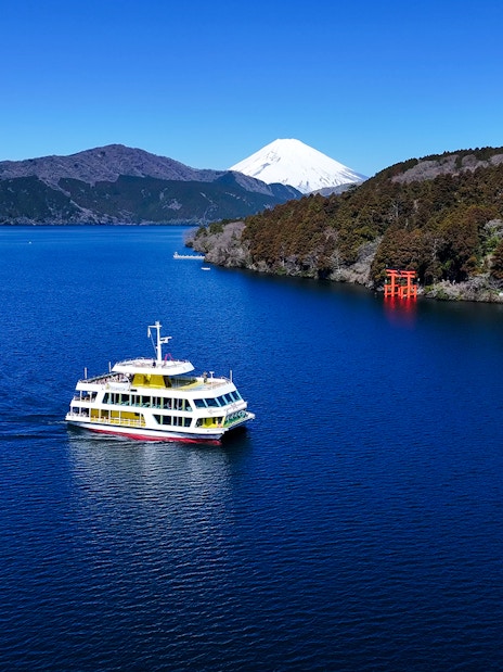 Boat on Lake Ashi with Mt Fuji and red torii gate in the background, Japan.