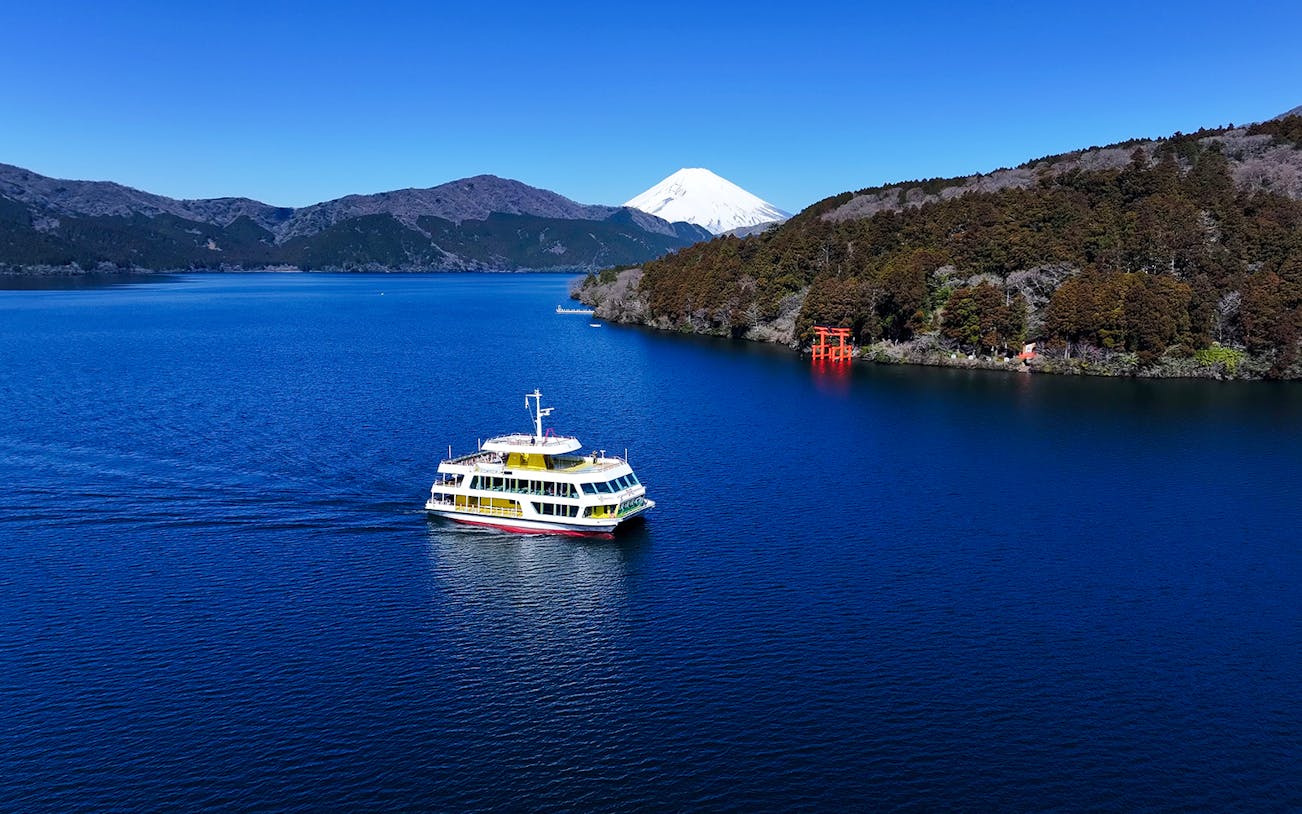 Mt Fuji reflected in Lake Ashi with a red torii gate in Hakone, Japan.