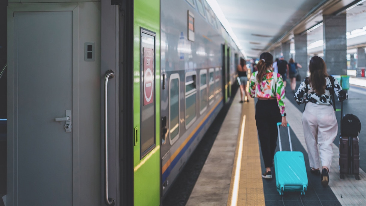 Passengers walking along Naples metro platform with train in view.
