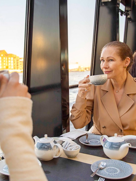 Afternoon tea on a Thames River cruise with people enjoying drinks and views of London.