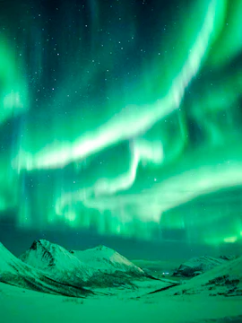 Northern Lights illuminating snowy mountains near Tromso, Norway.