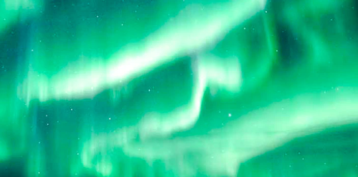 Northern Lights illuminating snowy mountains near Tromso, Norway.