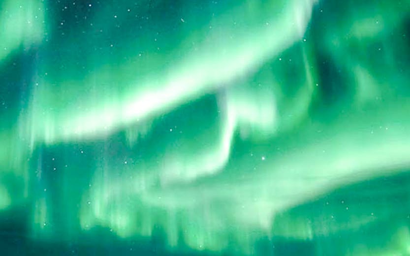 Northern Lights illuminating snowy mountains near Tromso, Norway.