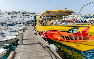 Yellow speedboat docked at marina, passengers boarding for Sunset Speedboat Dolphin Cruise.