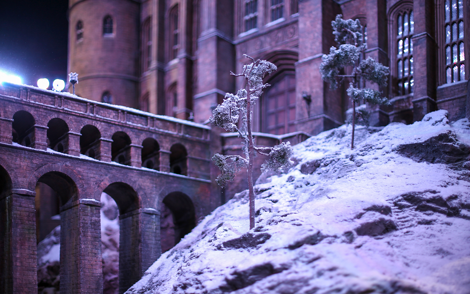 Snow-covered Hogwarts castle with bridge during Christmas season.