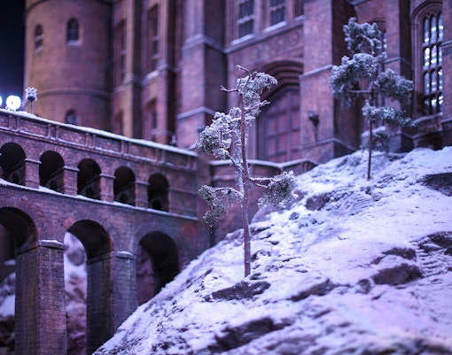 Snow-covered Hogwarts castle with bridge during Christmas season.