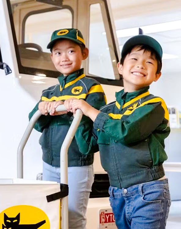 Children in delivery uniforms at KidZania Koshien, Tokyo, participating in a role-play activity.
