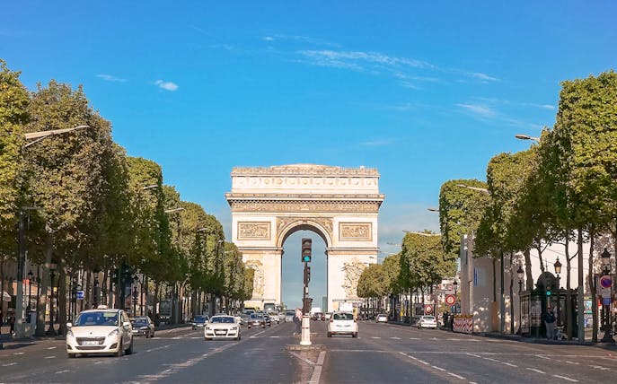 Arc de Triomphe viewed from Champs Elysées, Paris, with cars on the avenue.