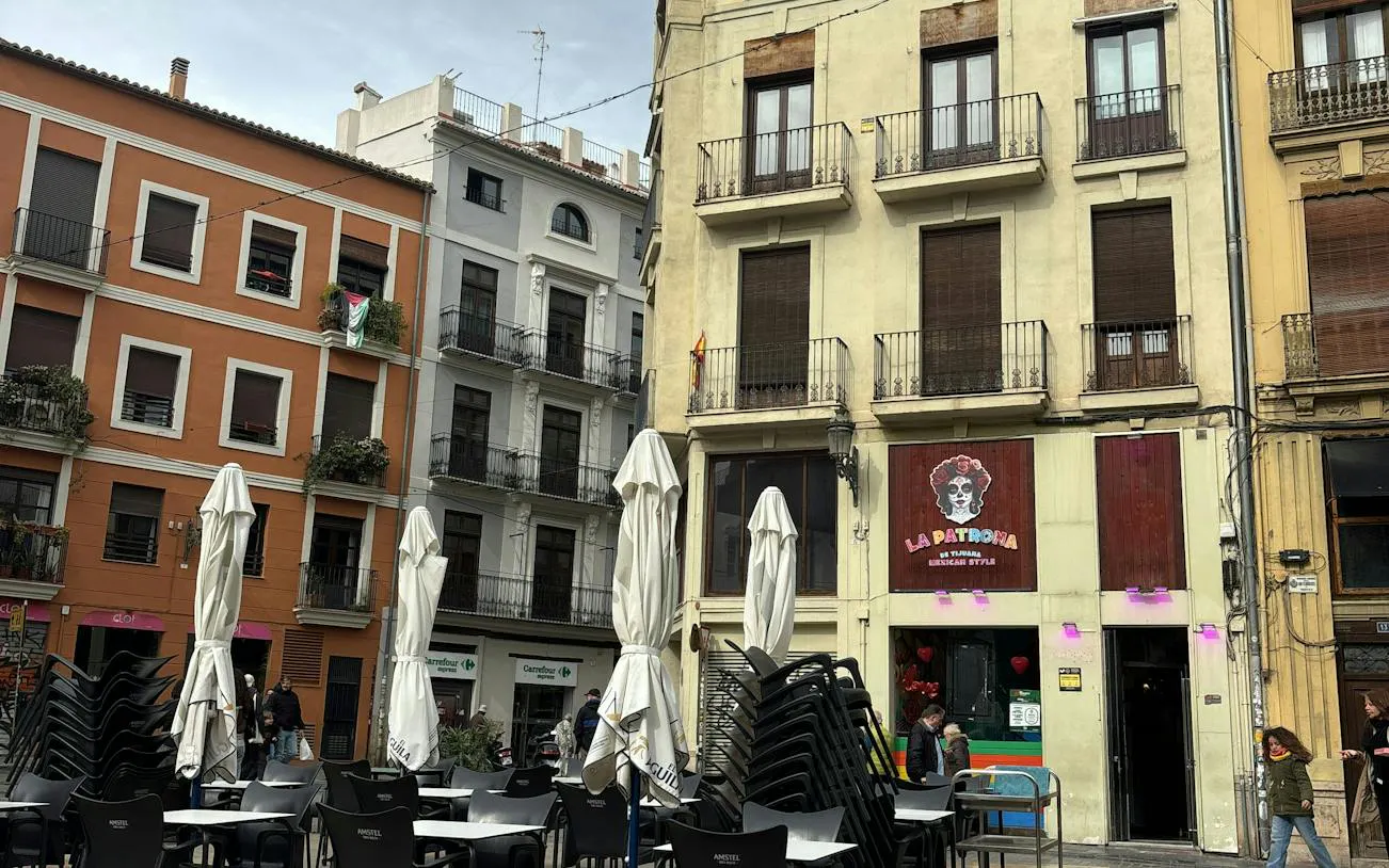 Outdoor café seating in Valencia's historic district, part of the Holy Grail city exploration game.