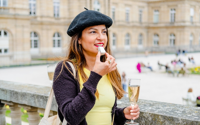 Woman enjoying cheese and wine at a Parisian landmark during Emily in Paris Food Tour.