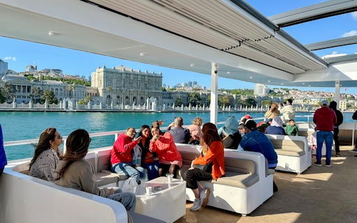 Guests enjoying a Bosphorus cruise with Dolmabahçe Palace in the background.