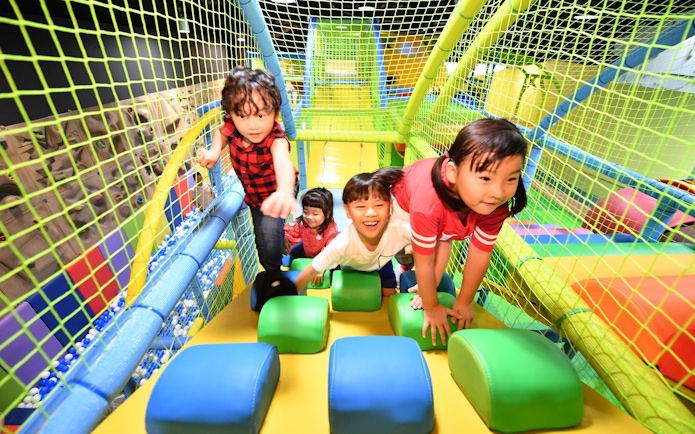 Children climbing play structure at Tayo Station indoor playground.