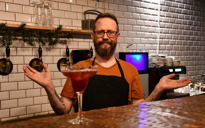 Local host in Icelandic restaurant with cocktail on bar counter.