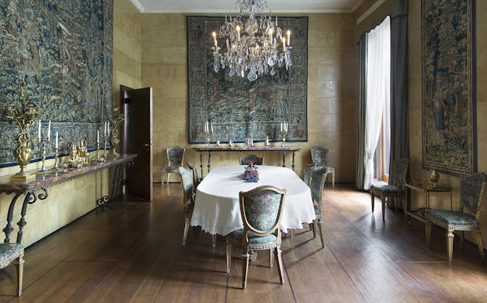 Elegant dining room with ornate chairs and tapestries in a Milan house museum.