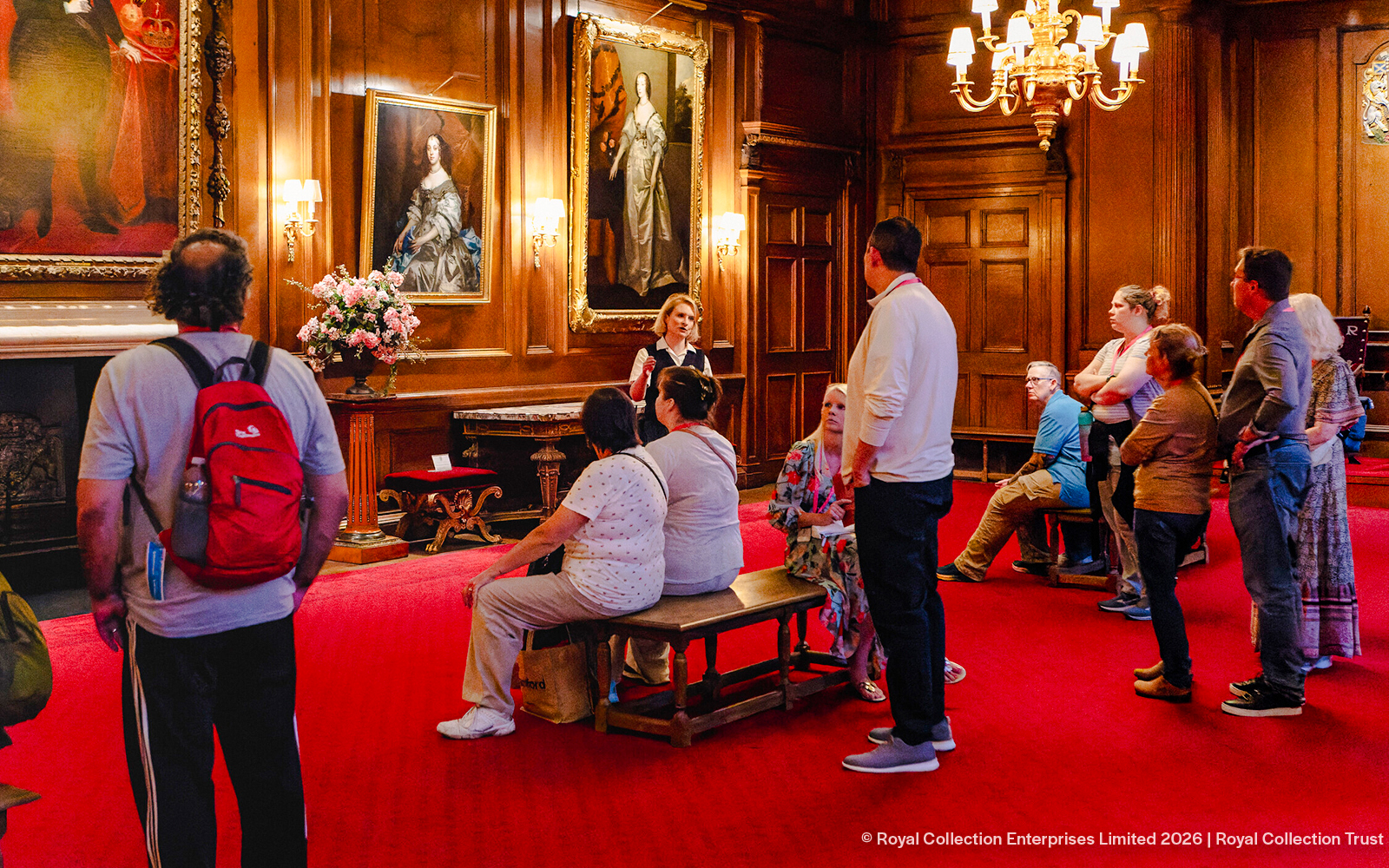 Tour group listening to a guide in the ornate gallery of the Palace of Holyroodhouse.