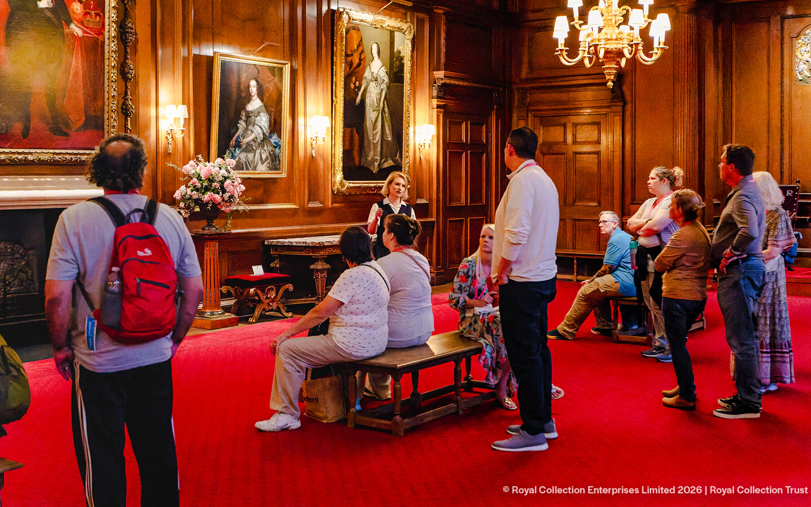 Tour group listening to a guide in the ornate gallery of the Palace of Holyroodhouse.