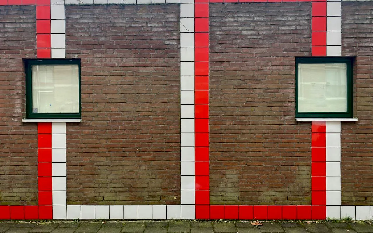 Brick wall with red and white tile stripes and two windows, Delft Food Tour, The Hague.